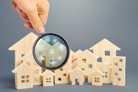 Realtor examines houses through a magnifying glass. Review of the real estate market, search for the best offers based on the criteria of price, location, area, infrastructure. Customer preferences.