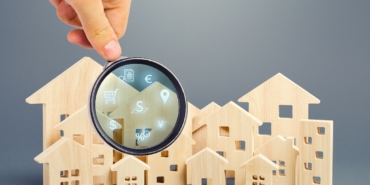 Realtor examines houses through a magnifying glass. Review of the real estate market, search for the best offers based on the criteria of price, location, area, infrastructure. Customer preferences.